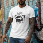 Man wearing a white t-shirt with 'SHOOTS BRAH' text against a graffiti wall.
