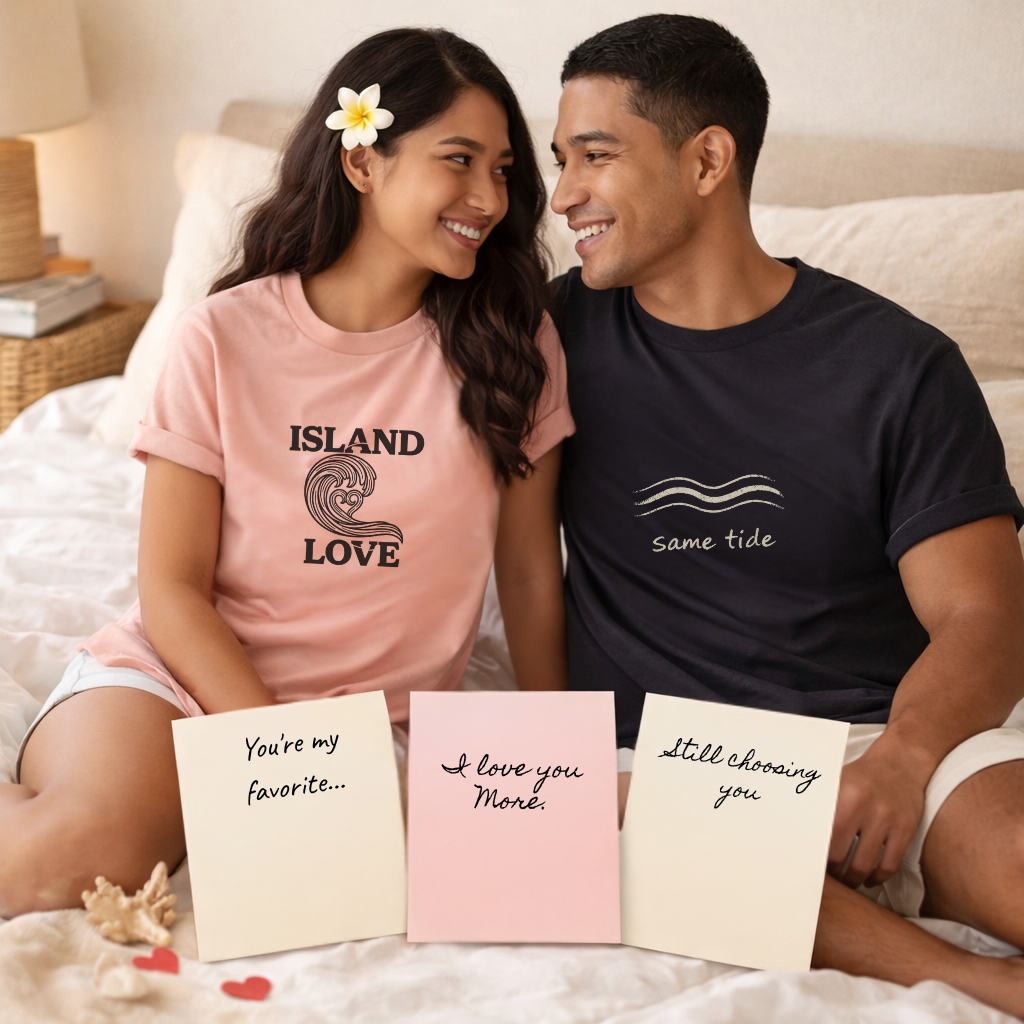 Couple sitting on a bed wearing matching t-shirts with romantic messages, holding cards.